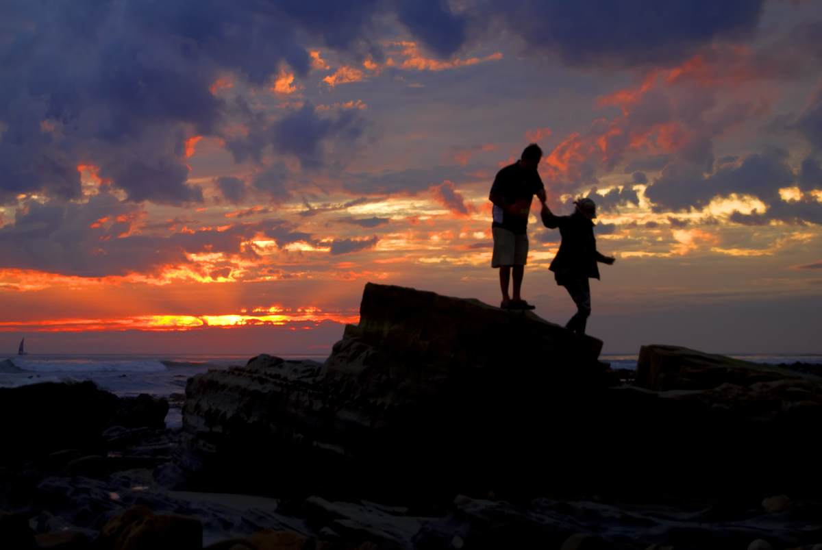 Mountaineers in silhouette hold hands at sunset - Wikimedia - Damian Gadal