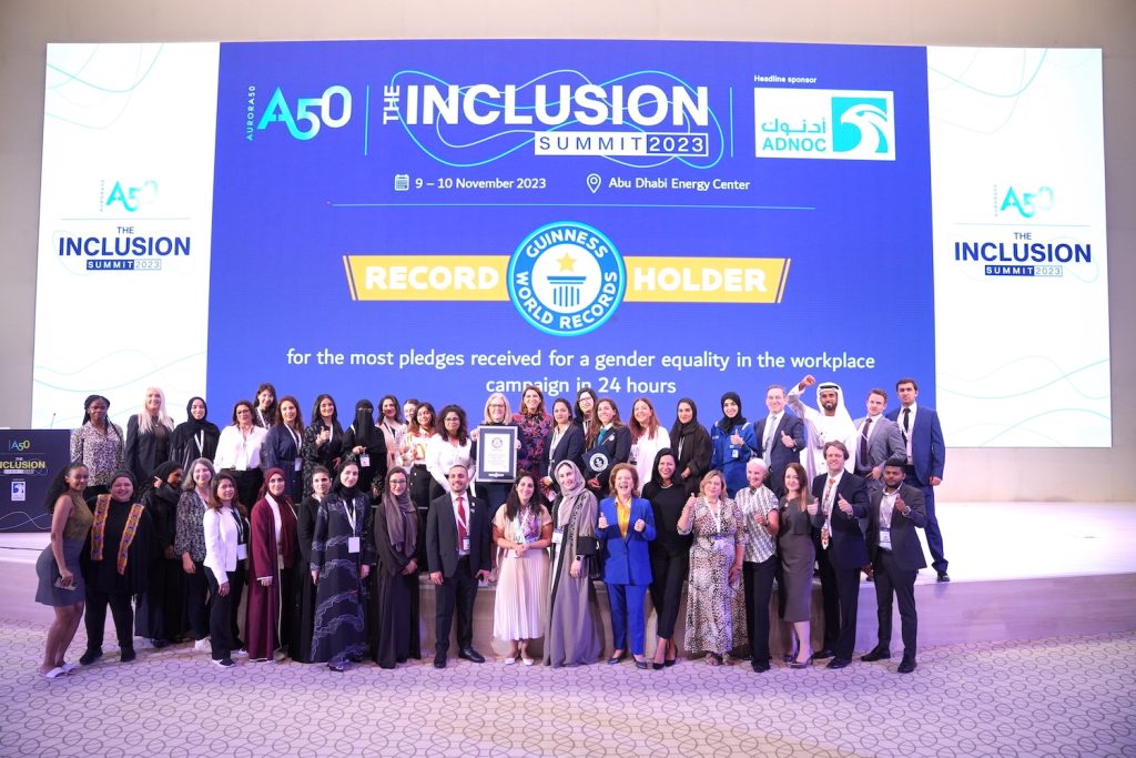 Aurora50 co-founder Diana Wilde holds the Guinness World Records certificate for 'most pledges to gender equality in the workplace in 24 hours campaign' surrounded by team and supporters at The Inclusion Summit 2023 in Abu Dhabi on 10 November 2023