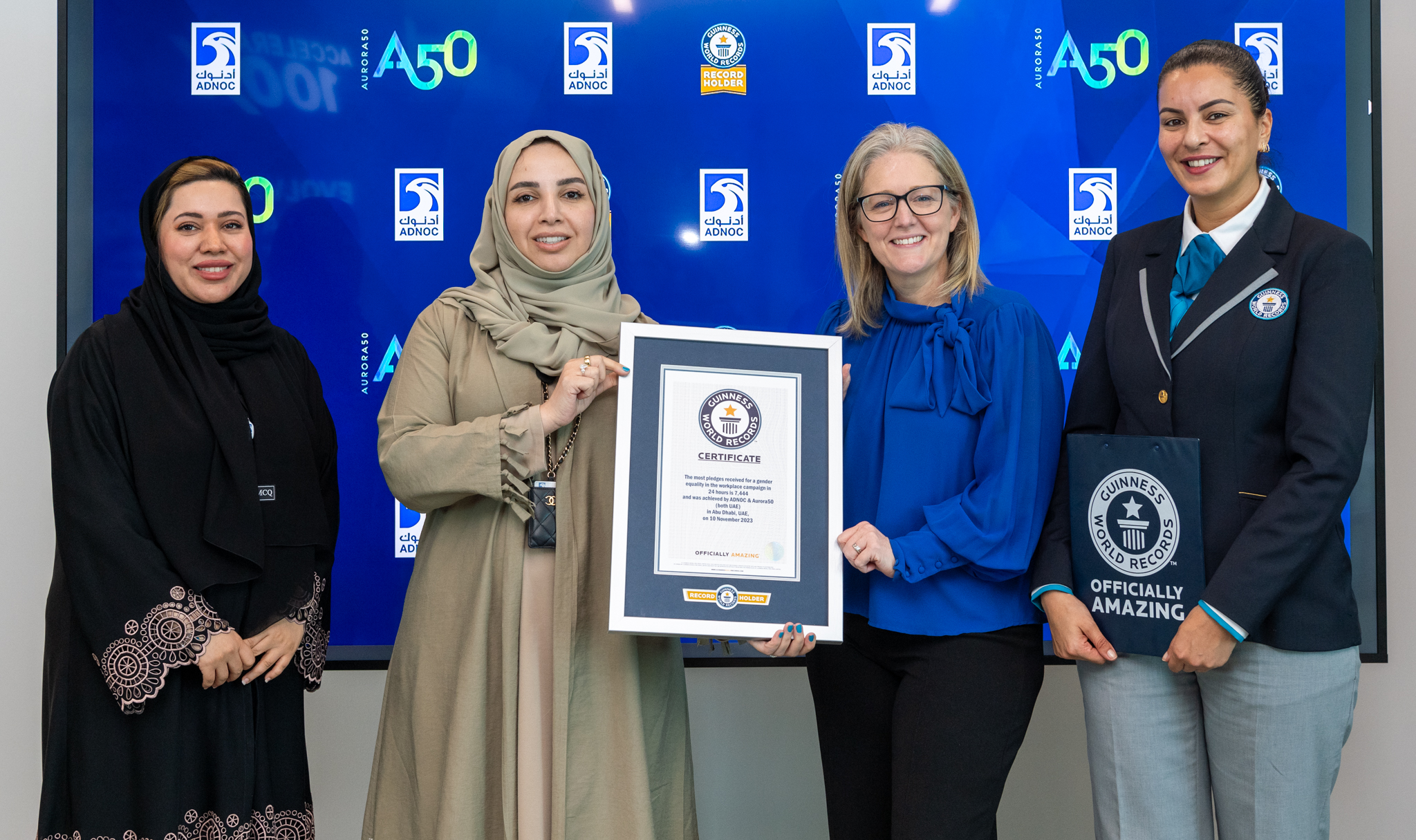 ADNOC's Fatema Al Nuaimi and Aurora50 co-founder Diana Wilde hold the Guinness World Records certificate at a February 2024 presentation ceremony of the certificate for the 'most pledges to gender equality in the workplace in 24 hours' campaign jointly won by the two companies in November 2023, as ADNOC's Eiman Alhammadi (L) and a Guinness World Records adjudicator (R) stand by their sides. Picture courtesy of ADNOC
